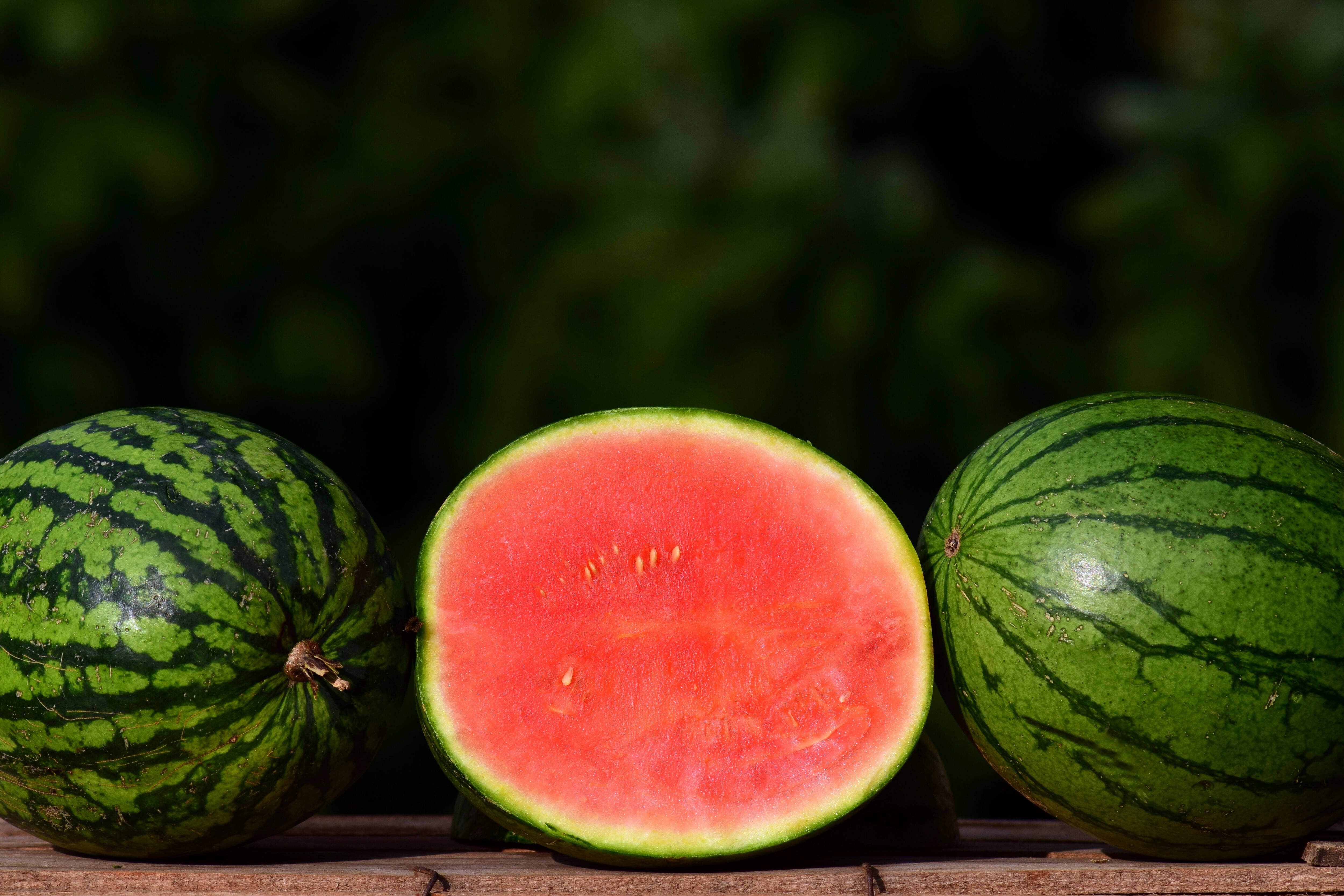 Three seedless water melons, the one in the middle is cut open.